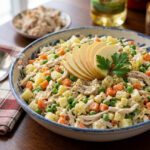 Ensalada de gallina venezolana con papa, zanahoria, guisantes y manzana verde en un tazón