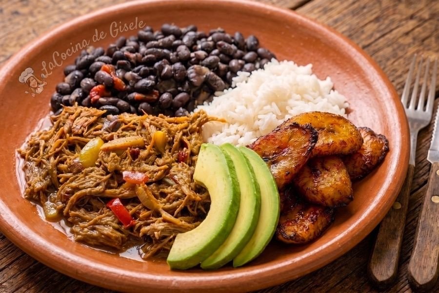 Pabellón criollo venezolano: carne mechada, caraotas negras, arroz blanco y tajadas de plátano maduro en un plato de barro