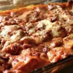 Pasticho venezolano tradicional recién horneado y gratinado con queso en una bandeja de vidrio, con capas de pasta, salsa de carne y salsa blanca